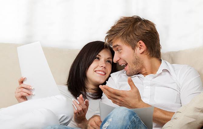 glückliches junges Paar auf einem Sofa, das sich über die Vorteiel der Förster-Qualitätsgarantie unterhält